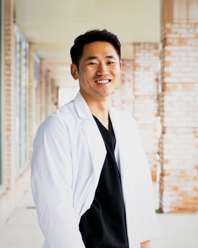 Dr. Yoodong Moon, DDS, smiling in a white coat